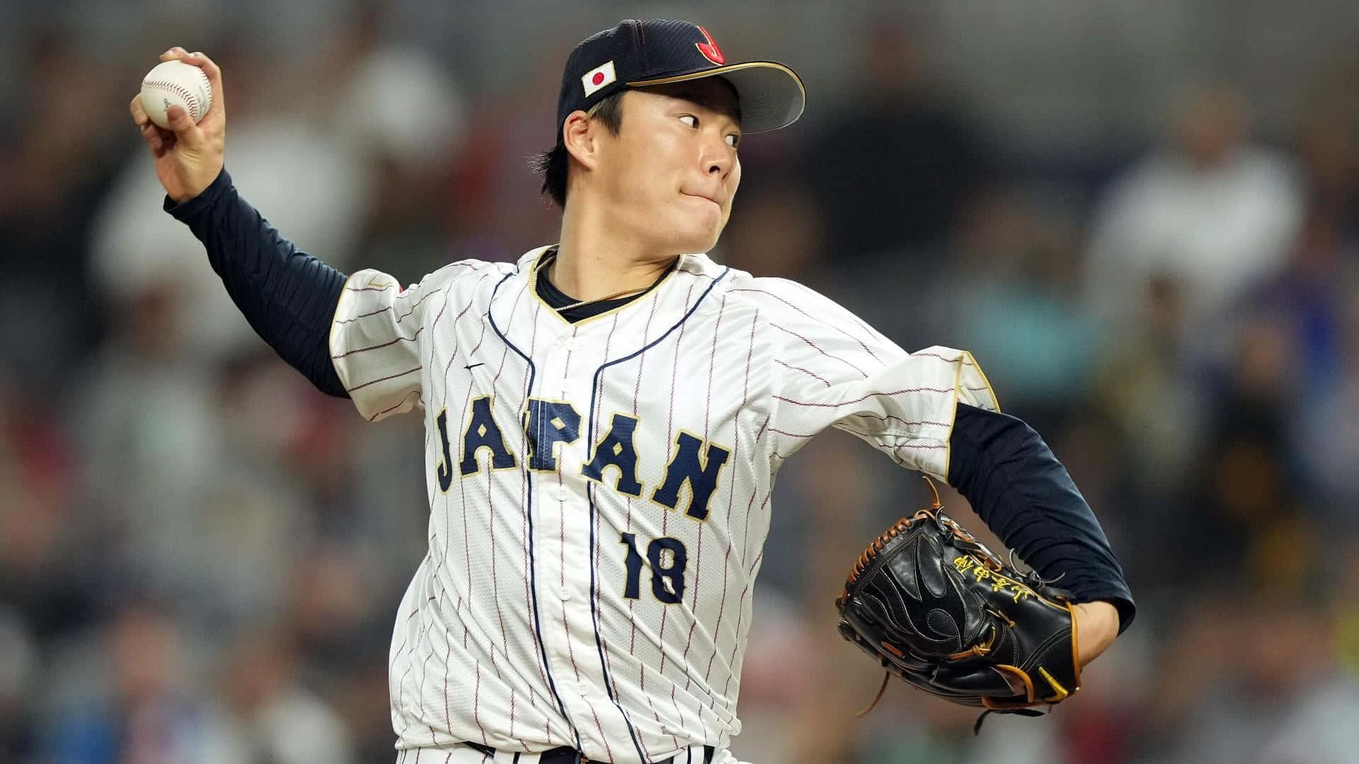  壁紙 — 一位身穿白色細條紋制服、背號18的日本棒球投手，在球場燈光下準備投球。