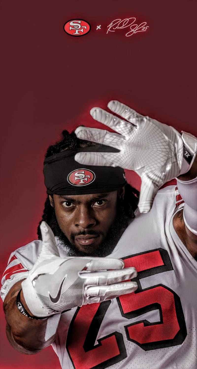 Richard Sherman 聖地牙哥49人隊 壁紙 — 一名身穿白色球衣和手套的三藩市49人美式足球員，在深紅色背景前擺出強烈的姿勢。