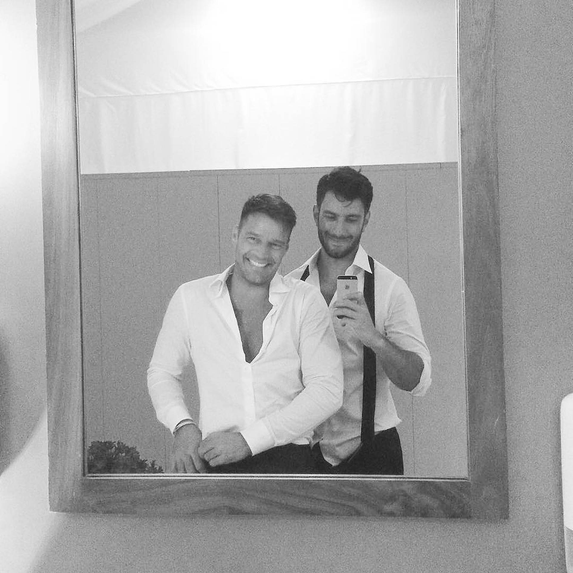 Ricky Martin 鏡頭自拍 壁紙 — 兩位微笑的男子在一個單色調的浴室中，帶有木框和白色窗簾，對著鏡子自拍。