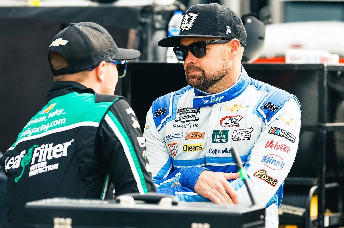 穿著賽車服的NASCAR車手在維修區與工作人員交談。