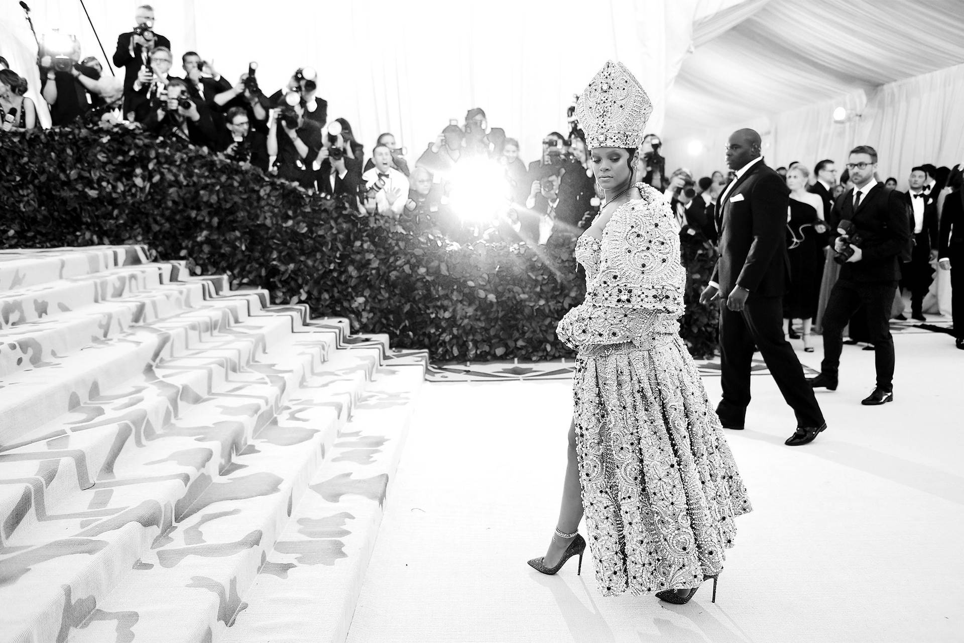 Rihanna 身穿華麗禮服，在攝影師簇擁下走下 Met Gala 樓梯。