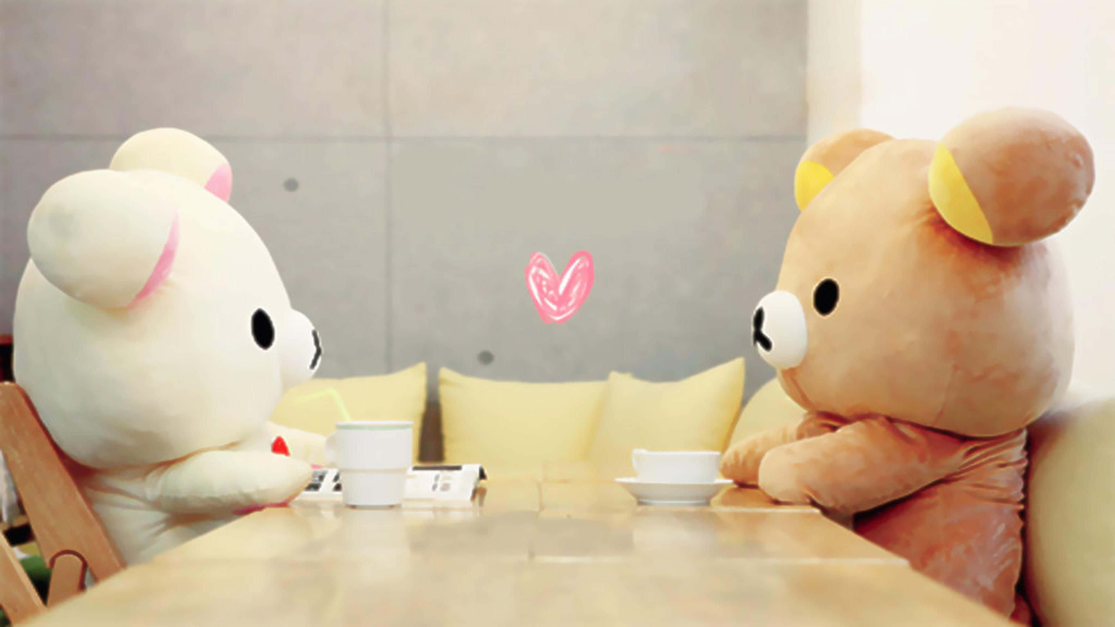 以 Rilakkuma 筆電獲得最可愛的優惠！ 壁紙 — 兩隻巨型毛絨熊坐在木桌兩邊分享茶，中間漂浮著一個粉紅色的心形。