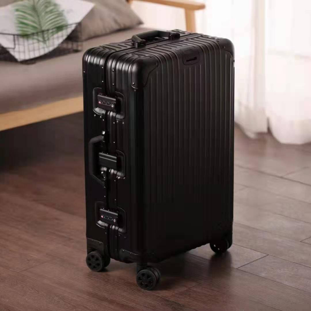 簡約黑色Rimowa行李箱 壁紙 — 一個時尚的黑色硬殼行李箱帶輪子，立在現代房間的木地板上，光線柔和。