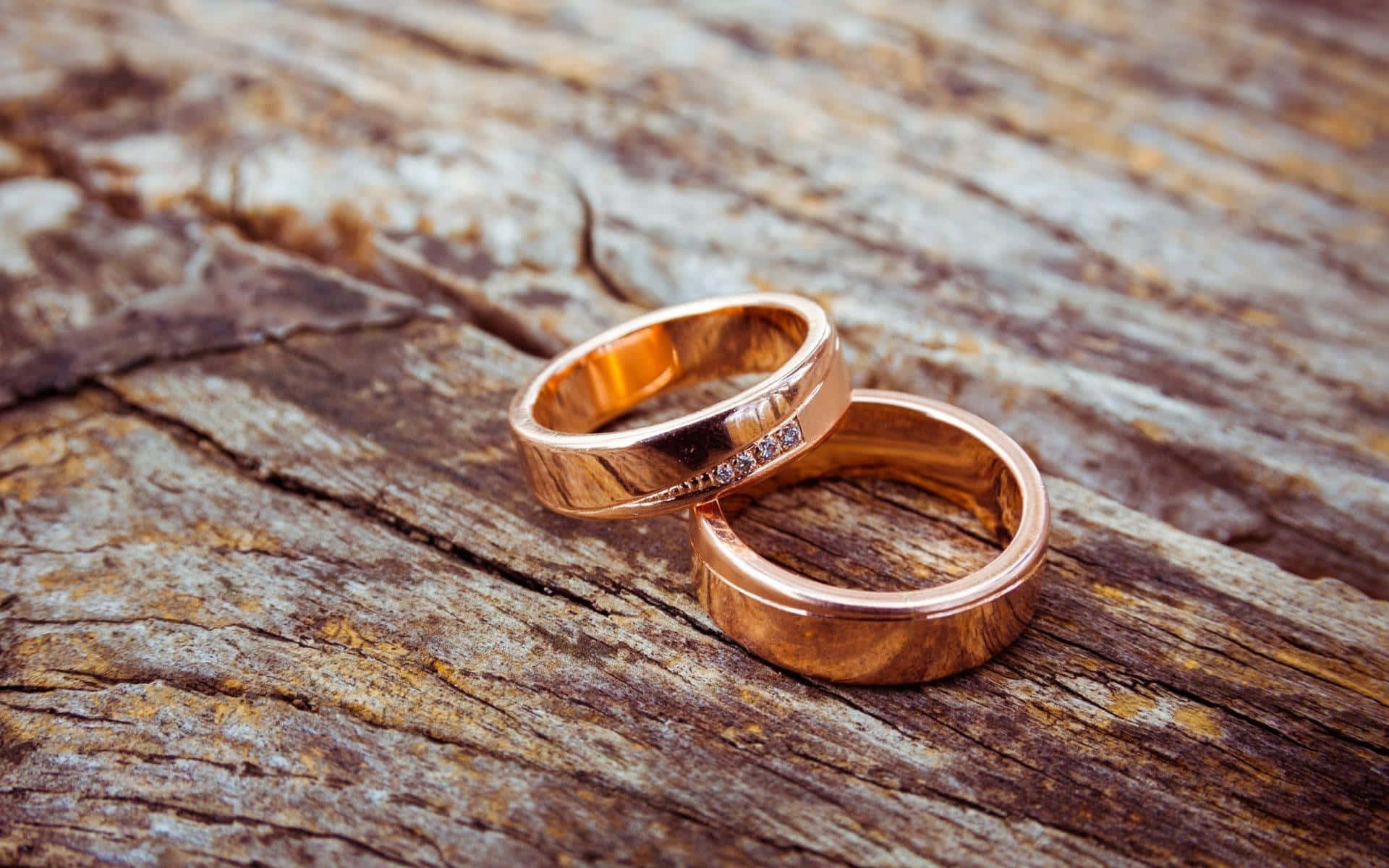 兩枚玫瑰金結婚戒指鑲有鑽石，放在質樸的木頭上。