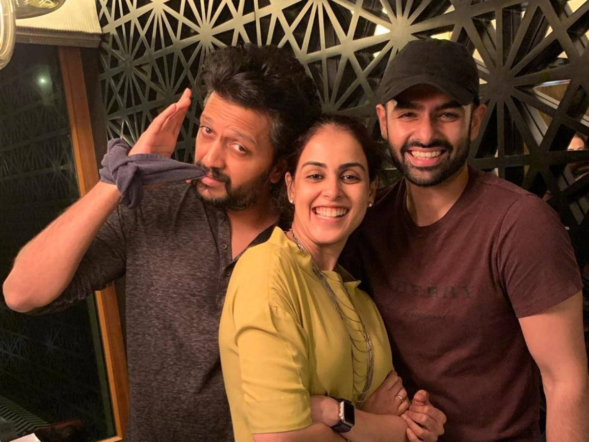 Riteish Deshmukh 與同劇演員合影 壁紙 — 三位微笑的朋友在室內對著幾何圖案牆壁，在溫暖燈光下俏皮地擺姿勢。