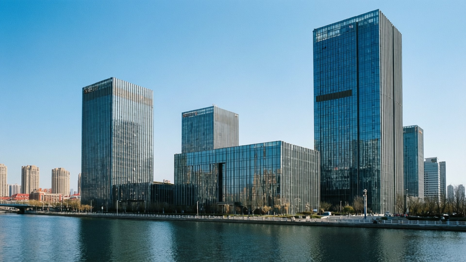 高聳的玻璃建築沿著平靜的河流排列，天空清澈湛藍。
