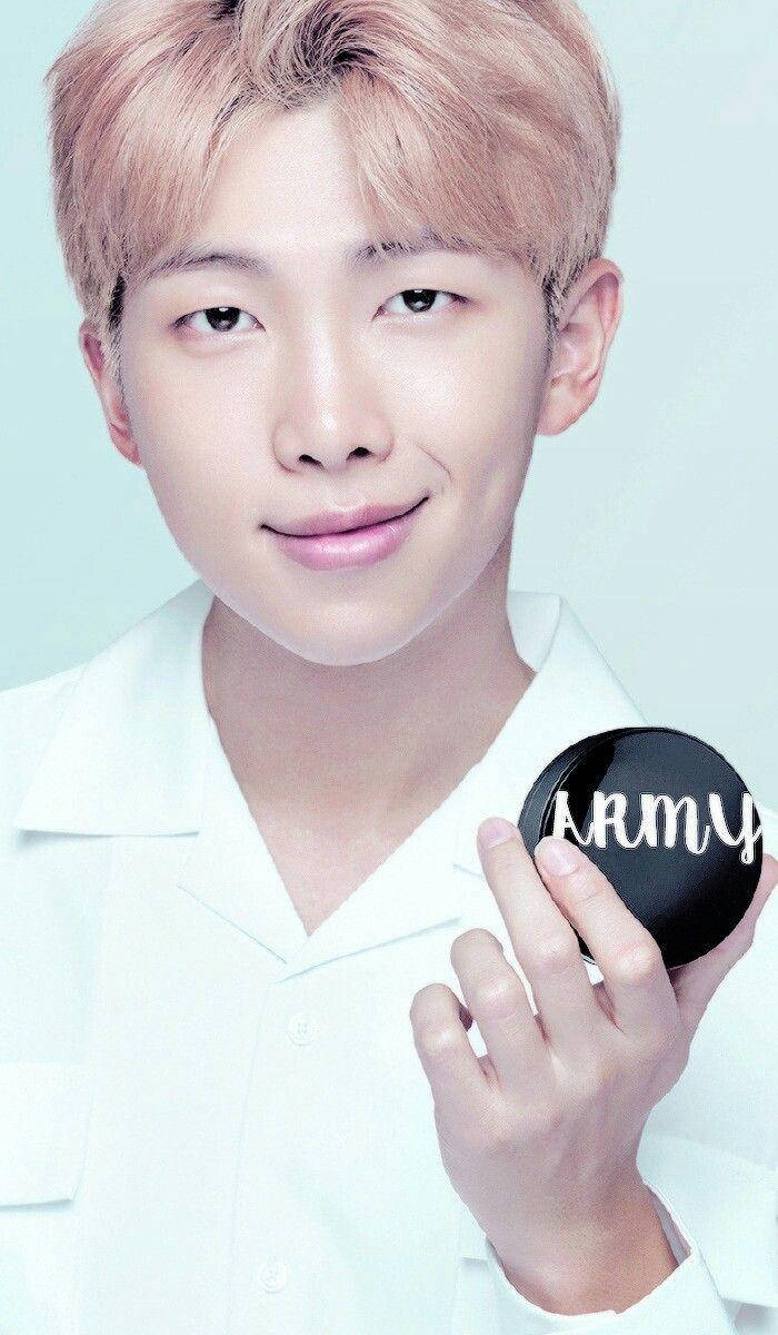 粉紅色頭髮的年輕男子手持一個寫有「ARMY」的黑色粉餅鏡。