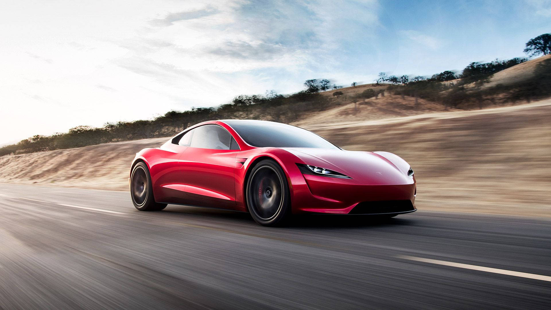特斯拉Roadster高速行駛 壁紙 — 一輛時尚的紅色Tesla Roadster在沙漠公路上疾馳，天空湛藍，白雲點點。