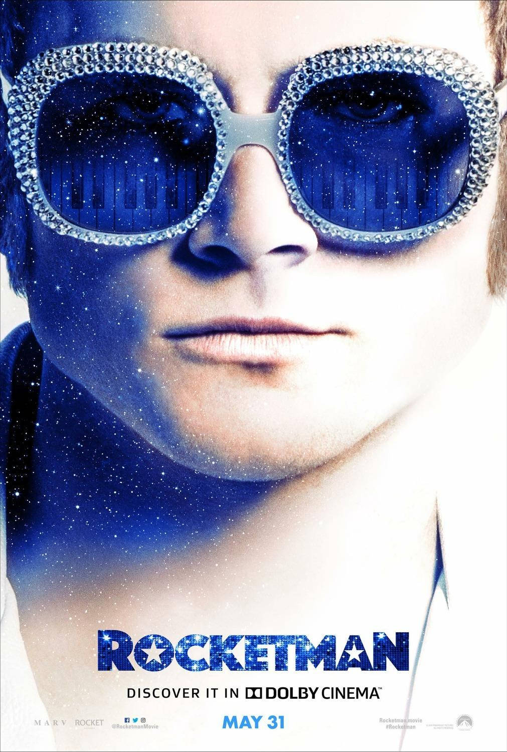 Rocketman 戴藍色時尚眼鏡 壁紙 — 一個男人戴著閃閃發光的藍色太陽眼鏡，鏡片上有星光鋼琴鍵反射，在宇宙藍色背景下凝視著。