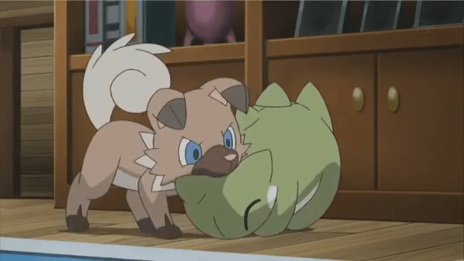 Rockruff 與玩偶 壁紙 — 一隻堅定的動畫小狗在木地板上靠近櫃子處蹭著一個正在睡覺的綠色生物。
