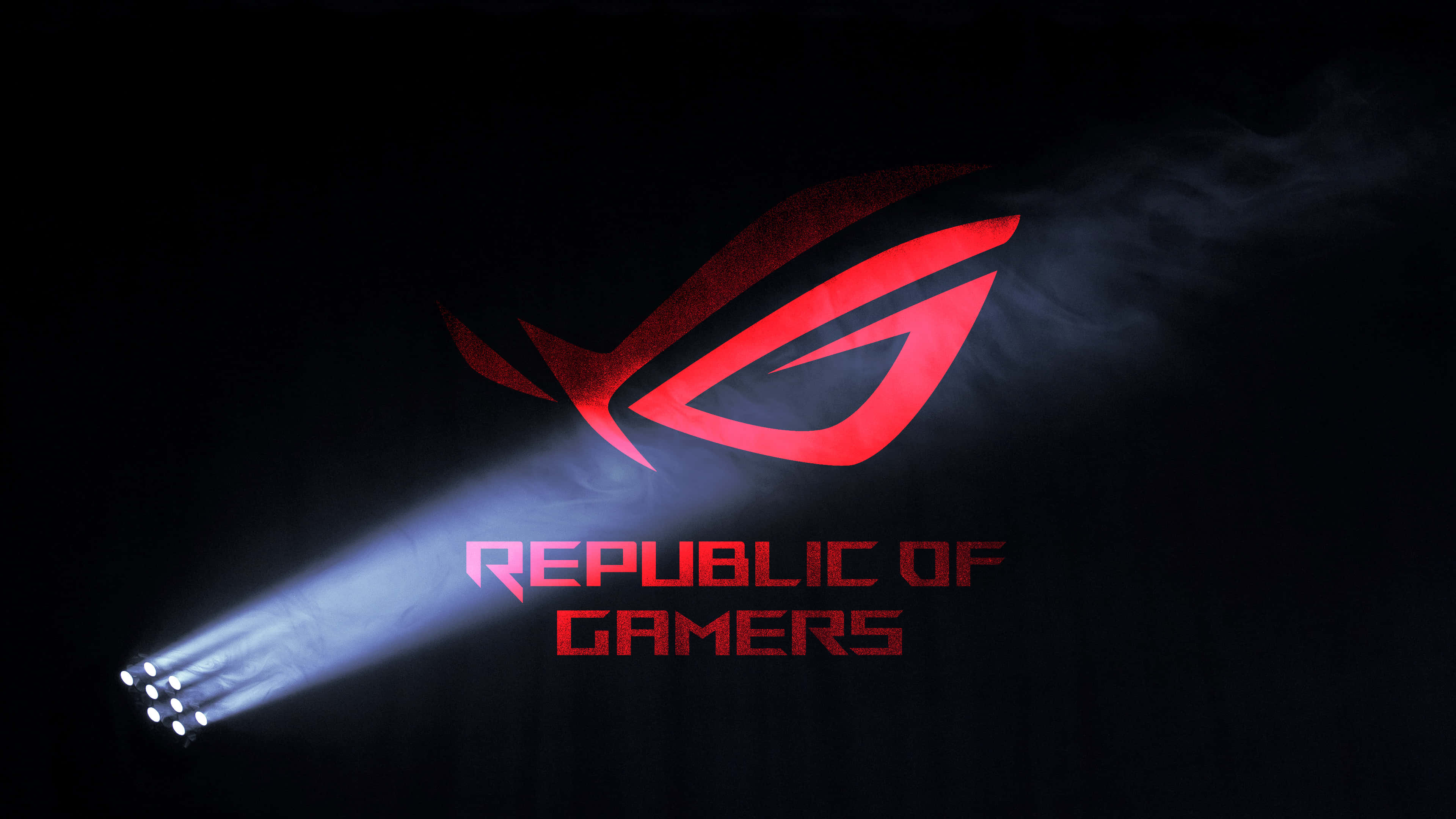 ROG 遊戲 – 無與倫比的桌面效能 壁紙 — 一個發光的紅色ROG標誌，被聚光燈照亮，背景是黑暗煙霧瀰漫，帶有「Republic of Gamers」文字。