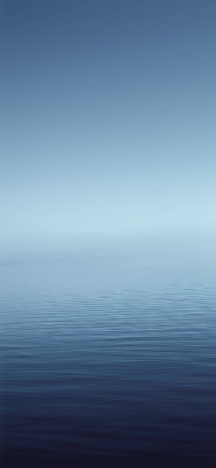 平靜的藍色水面在黎明時分與天空相遇，泛起輕柔漣漪