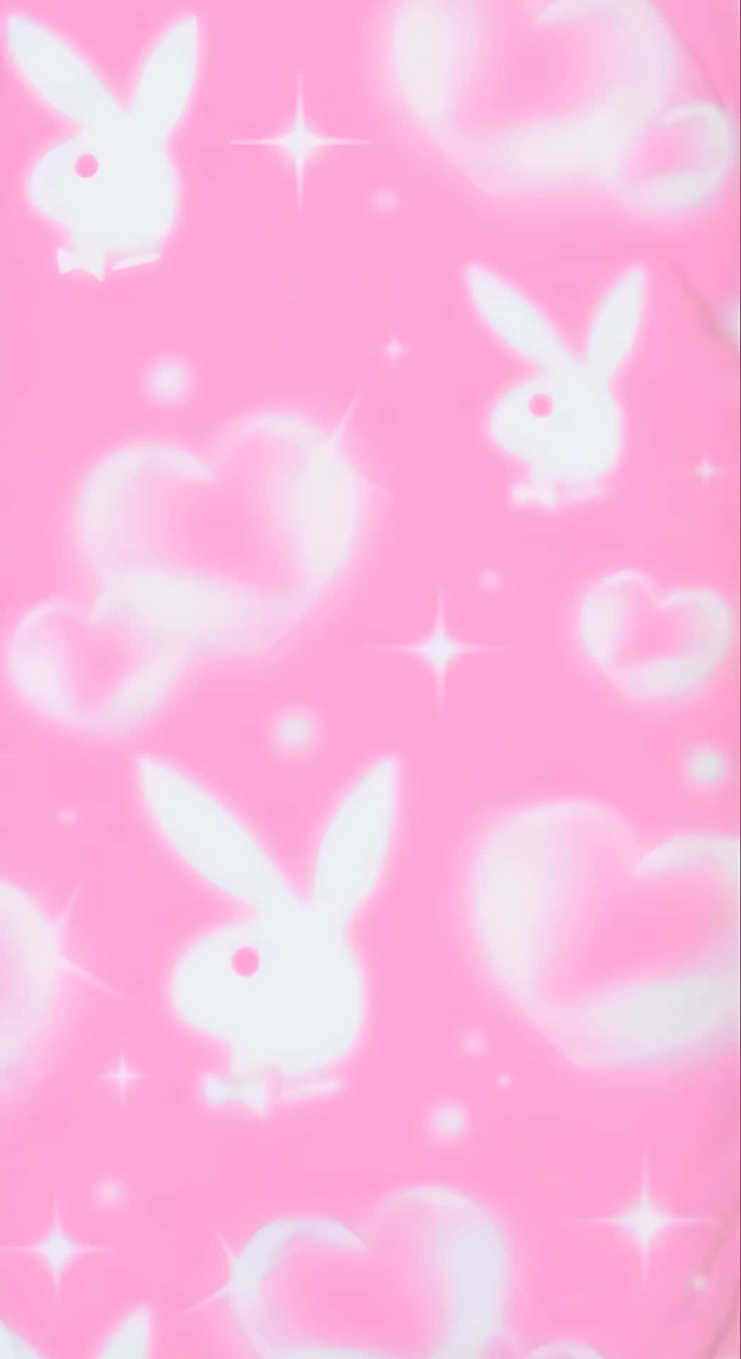  壁紙 — 柔軟的粉紅色牆紙，帶有發光的白色Playboy兔子和心形圖案，漂浮在閃爍的星星之間。