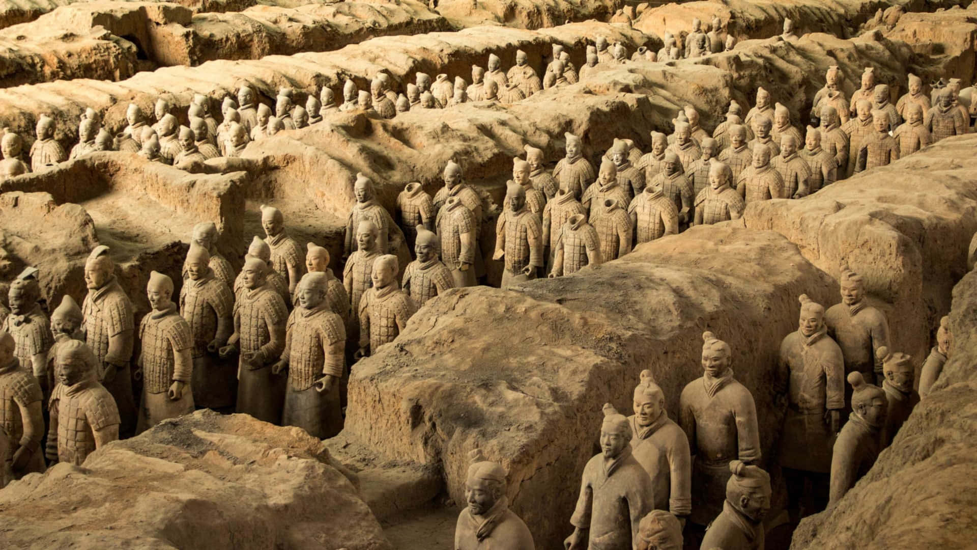  壁紙 — 一排排古老的兵馬俑站在土坑中，在溫暖的陽光下展現出精緻的盔甲和莊嚴的表情。