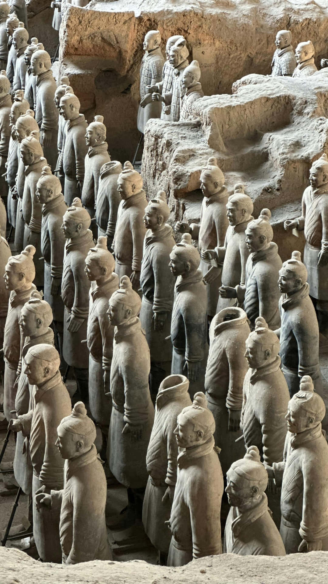  壁紙 — 一排排古老的兵馬俑以大地色調矗立於其發掘坑中，每個都有獨特的面部細節和盔甲。