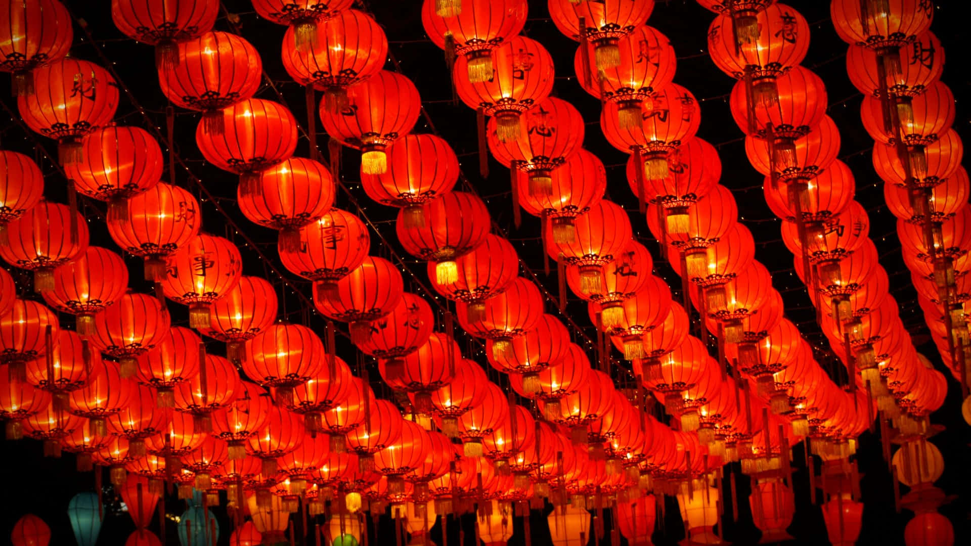  壁紙 — 一排排帶有中文字的發光紅色紙燈籠密密麻麻地掛在漆黑的夜空下。