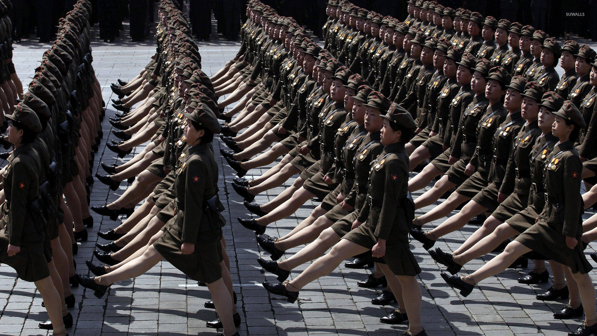 身穿制服的女兵在鋪砌的廣場上以精確的隊形行進。