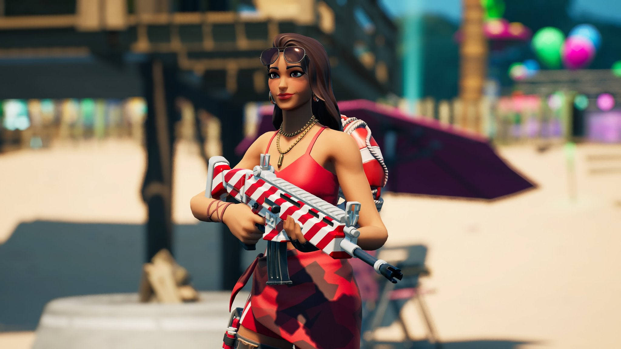 Ruby《Fortnite》海灘救生員 壁紙 — 一位身穿紅色服裝的女性遊戲玩家在陽光明媚的海濱廣場上，手持一支條紋步槍，周圍有彩色氣球和遮陽傘。