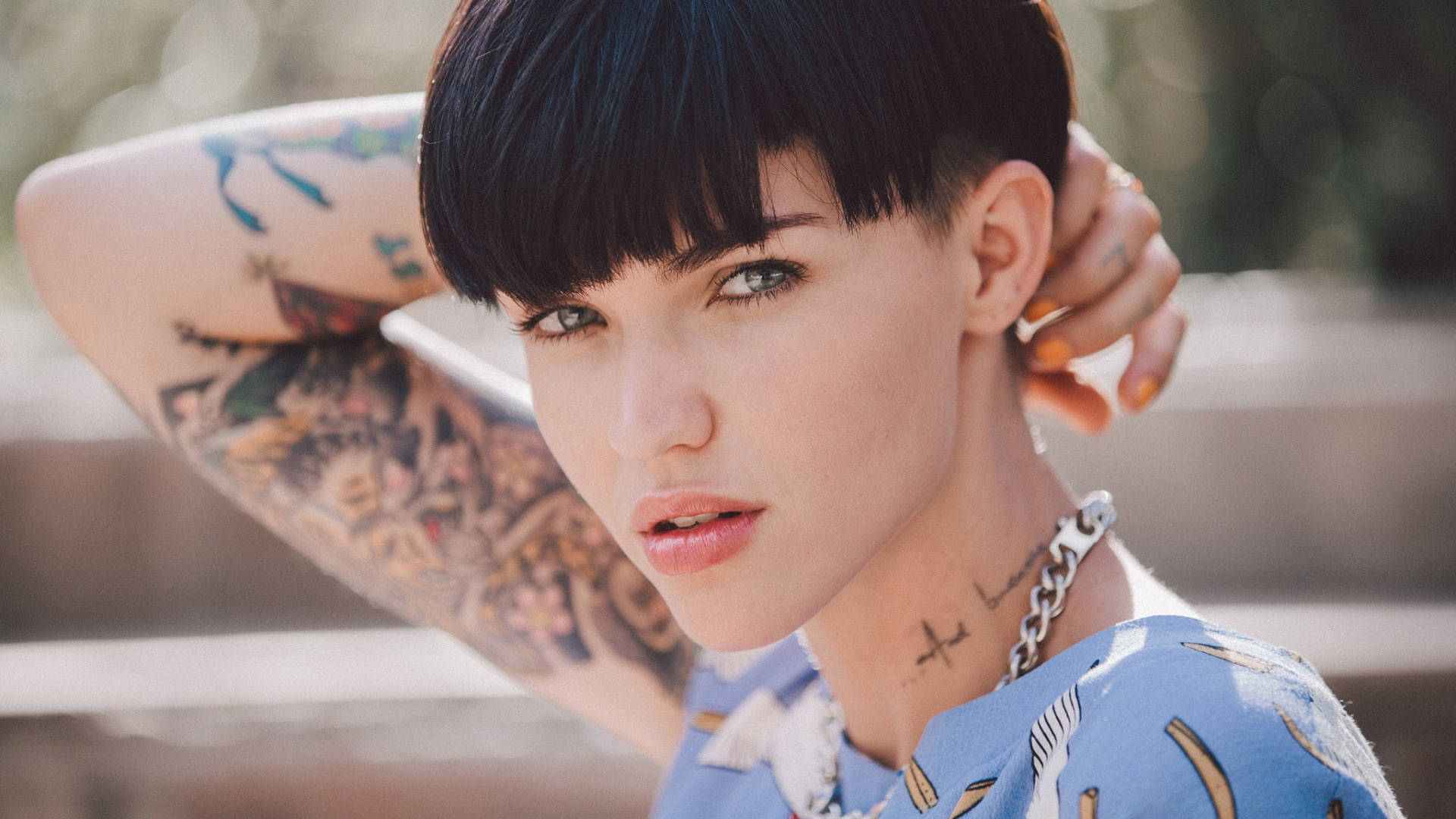 Ruby Rose 潮流碗髮造型 壁紙 — 一位短黑髮、有紋身的年輕女性直視鏡頭，同時觸摸頸部。
