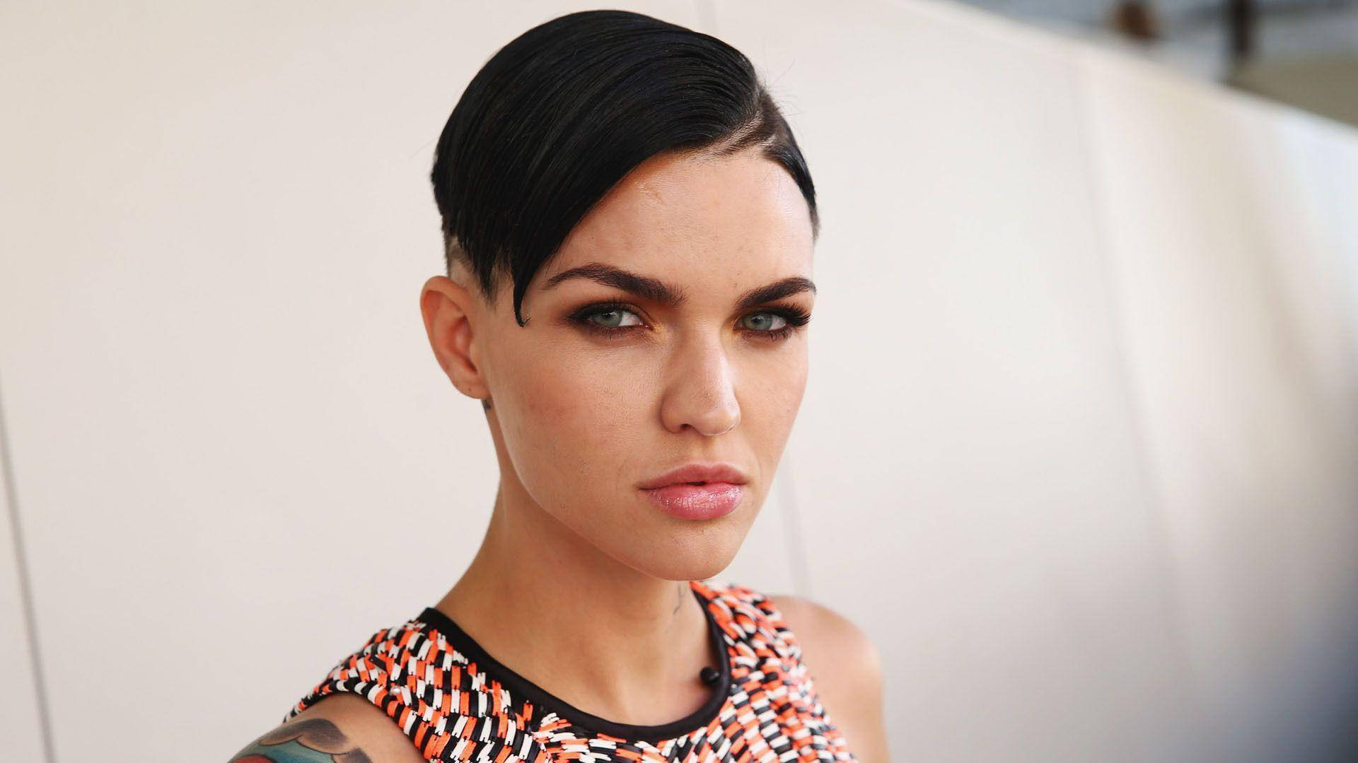 Ruby Rose 頂級 undercut 髮型 壁紙 — 一位短黑髮、妝容大膽的女性，穿著色彩繽紛的幾何圖案上衣，專注地凝視著鏡頭。