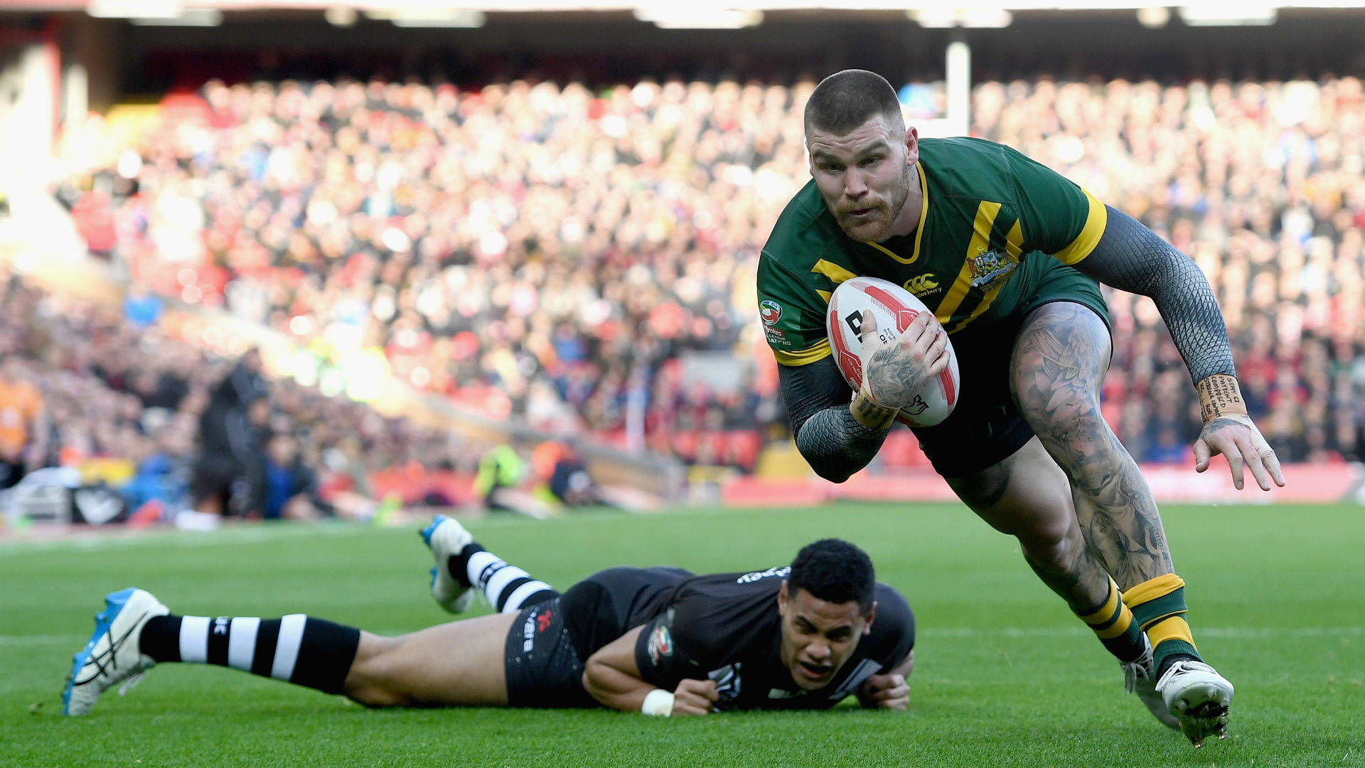 rugby 比賽攝影 壁紙 — 一名身穿綠色和黃色球衣的欖球運動員帶著球向前飛撲，而一名身穿黑色的防守球員在充滿活力的綠色球場上對他進行攔截。