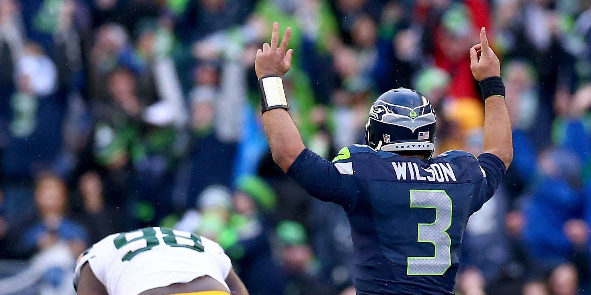 Russell Wilson 指手畫腳 壁紙 — 西雅圖海鷹隊四分衛拉塞爾·威爾遜在體育場人群中高舉雙臂慶祝。