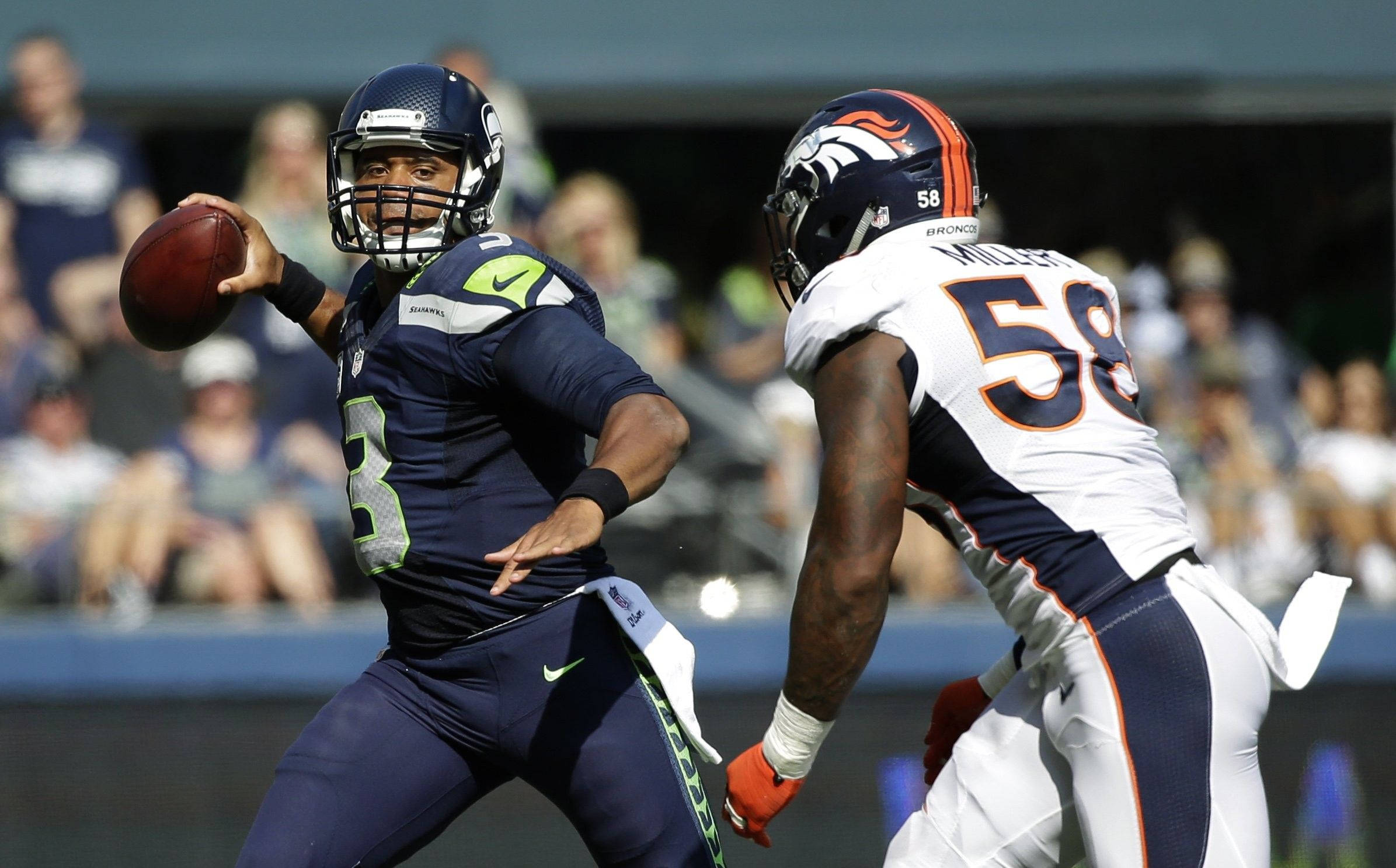Russell Wilson 被阻擋 壁紙 — 西雅圖海鷹隊四分衛羅素·威爾遜在日間NFL比賽中擲出橄欖球，丹佛野馬隊線衛馮·米勒衝刺過來。