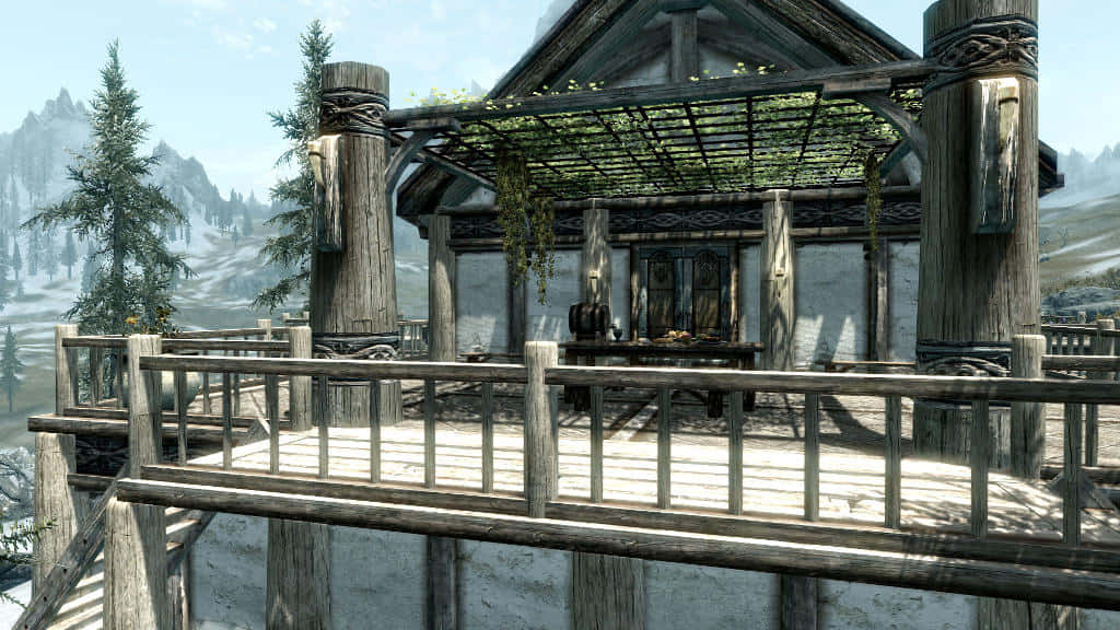 Heljarchen Hall 桌布 壁紙 — 一個質樸的木製涼亭，屋頂覆蓋著藤蔓，矗立在白雪覆蓋的山頂觀景點，周圍環繞著常青樹和遠處的山峰。