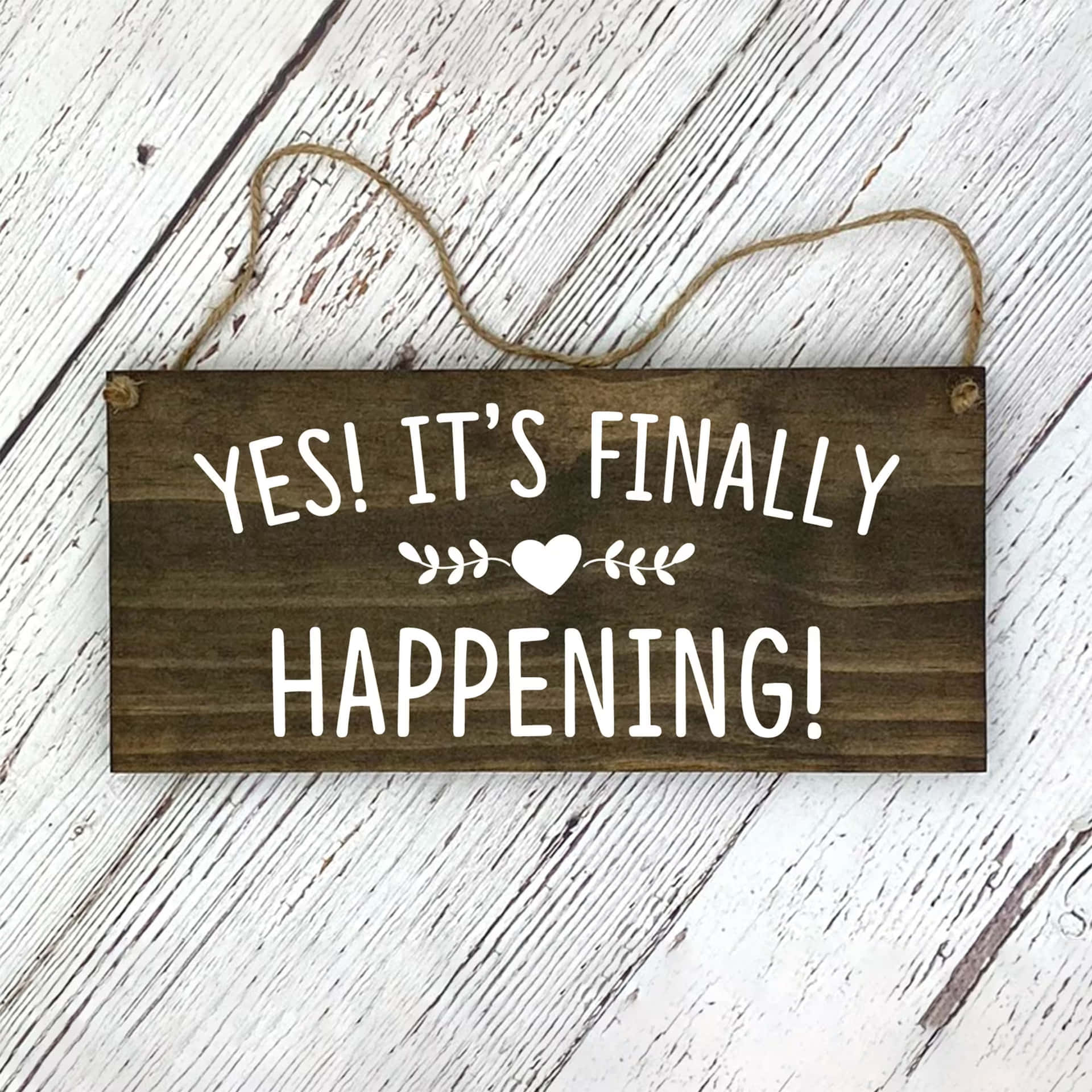  壁紙 — 一個質樸的木牌，上面有白色文字寫著「YES! IT'S FINALLY HAPPENING!」，掛在風化的白色木質表面上。
