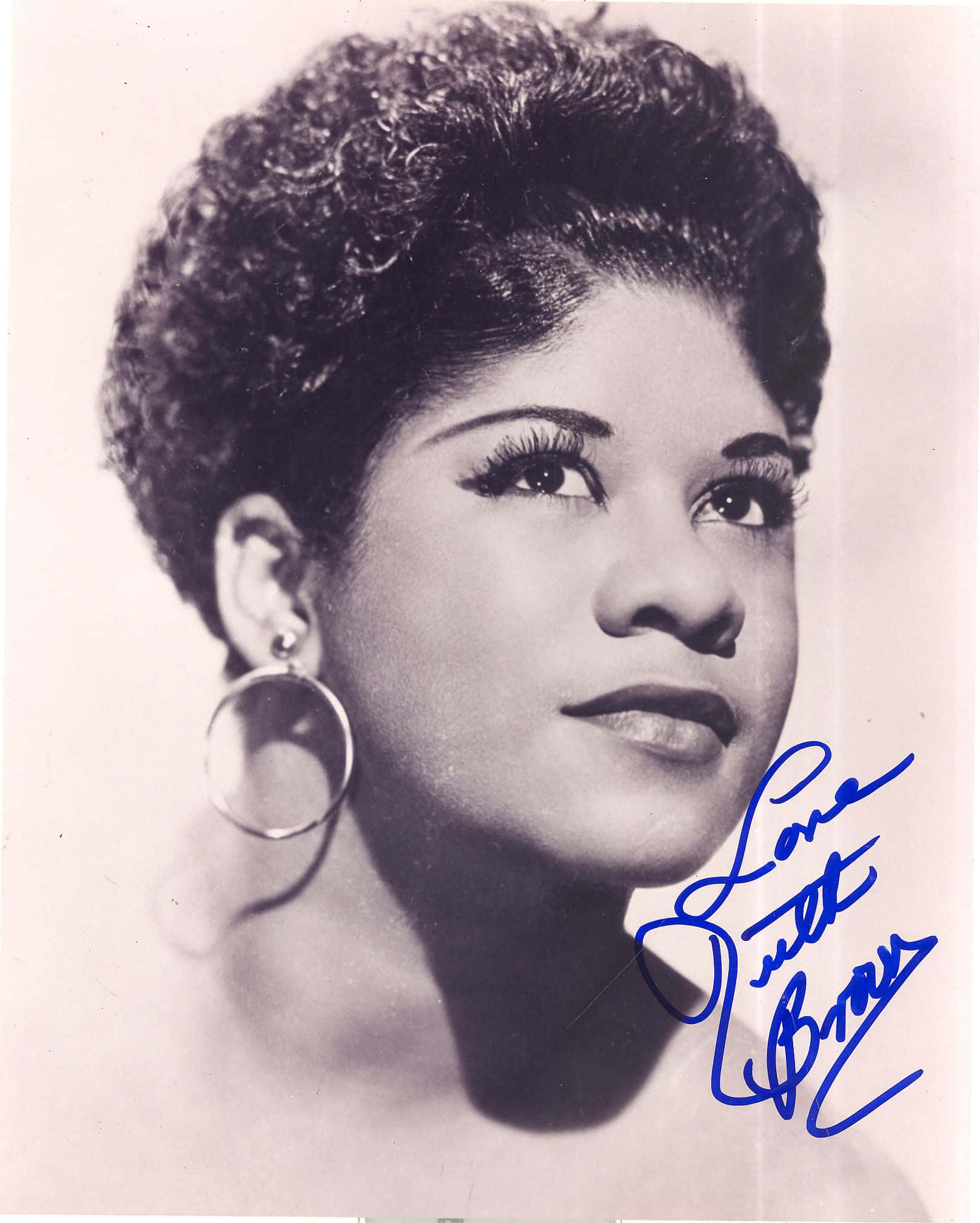 Ruth Brown 簽名照 壁紙 — 歌手Loretta Brown的復古黑白肖像，擁有豐盈捲髮和大圈耳環，向上凝視。