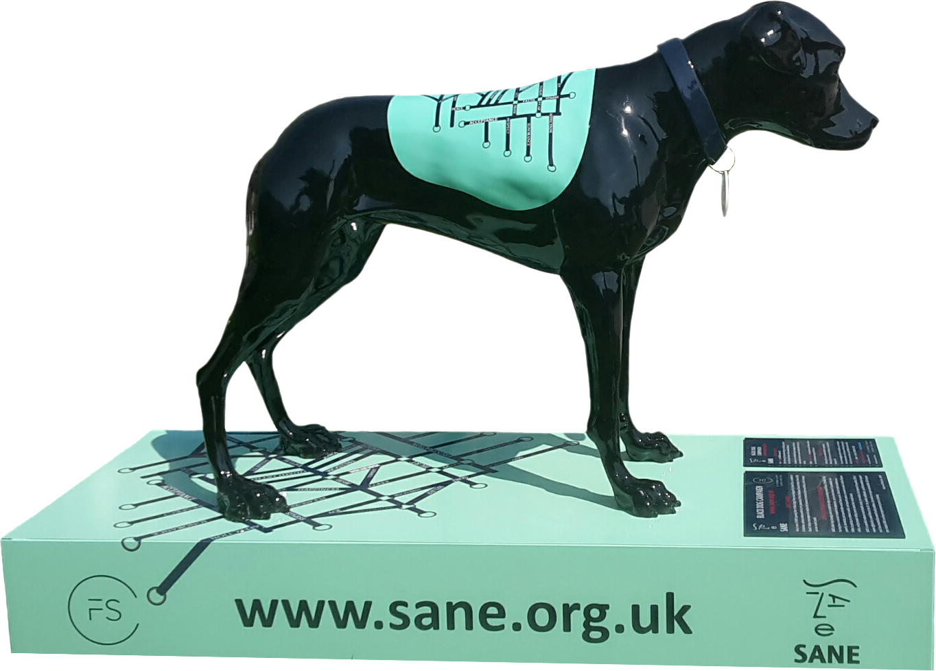 黑灰色獵犬雕塑 S A N E 慈善機構 壁紙 — 一隻光滑的黑色狗雕像穿著帶有工具圖案的青綠色背心，站在一個匹配的青綠色盒子上，顯示SANE網站。