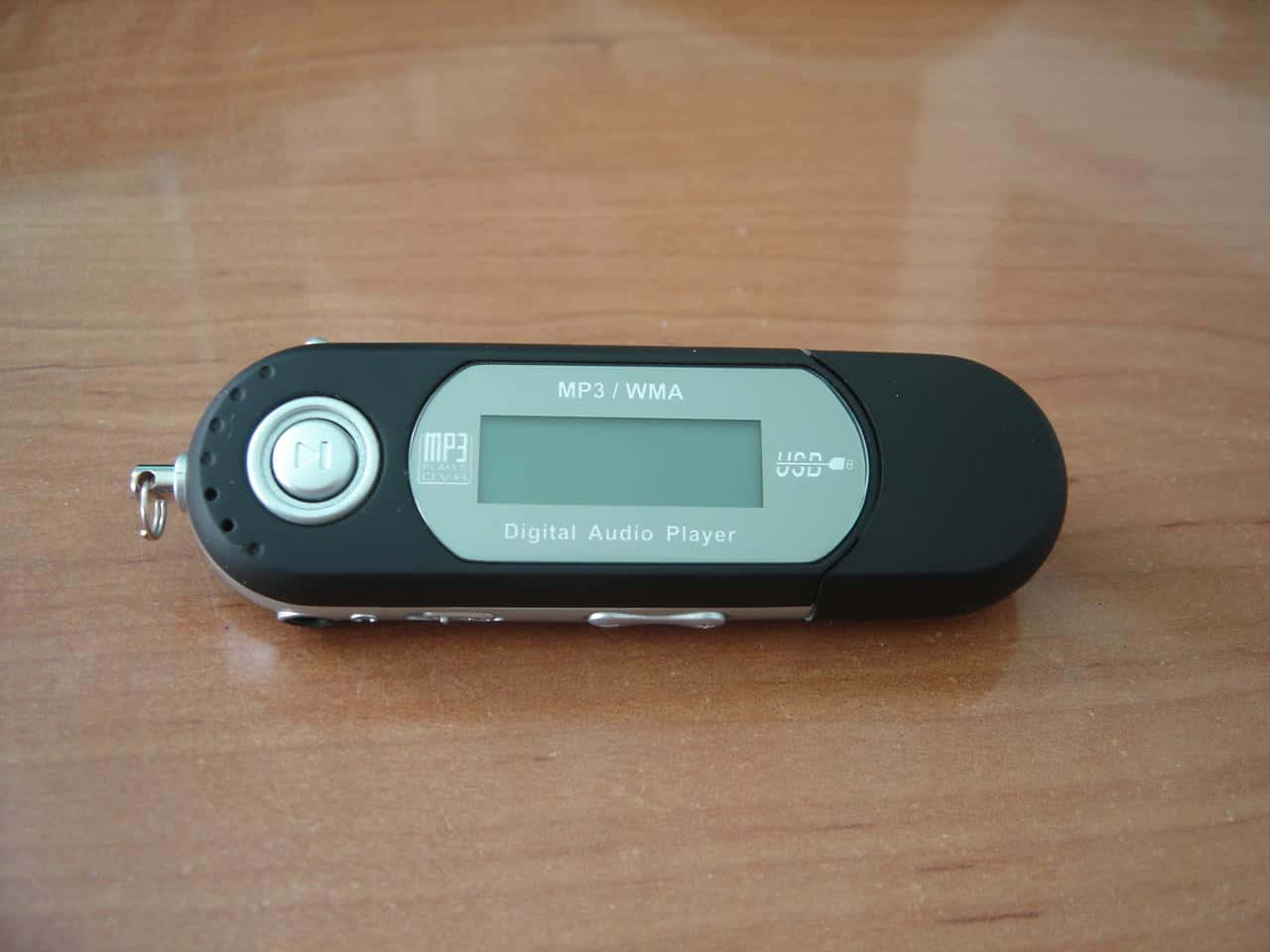 S1 MP3播放器圖片 壁紙 — 一部黑色數碼音頻播放器帶有銀色點綴，放置在溫暖的木質表面上。
