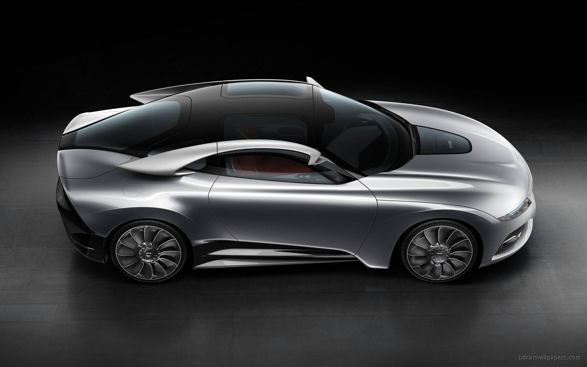 Saab PhoeniX 概念車 壁紙 — 一輛時尚的銀色未來主義跑車，帶有黑色車頂和發光裝飾，在黑暗的攝影棚中展示。