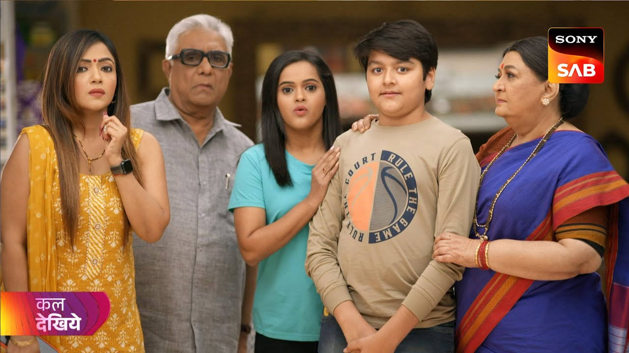 索尼SAB《Wagle Ki Duniya》劇組群像 壁紙 — 一個五口之家在溫暖照明的室內場景中站在一起，穿著色彩繽紛的傳統和休閒服裝。