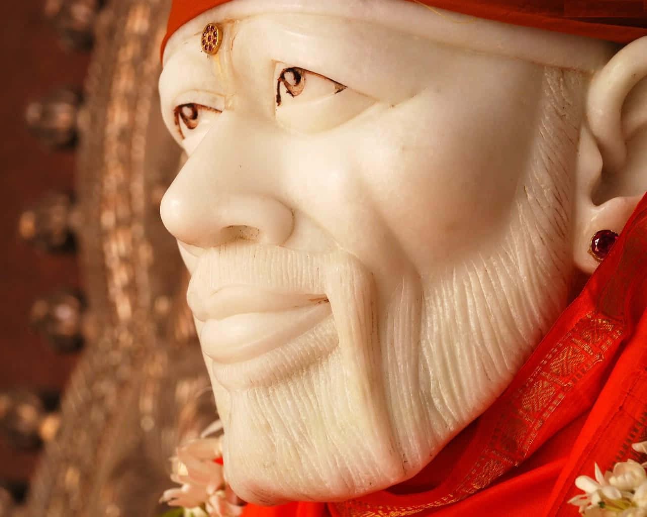 希迪 Sai Baba 塑像特寫 壁紙 — 一位戴紅色頭飾和花卉裝飾的老年男子的寧靜白色大理石雕像特寫。