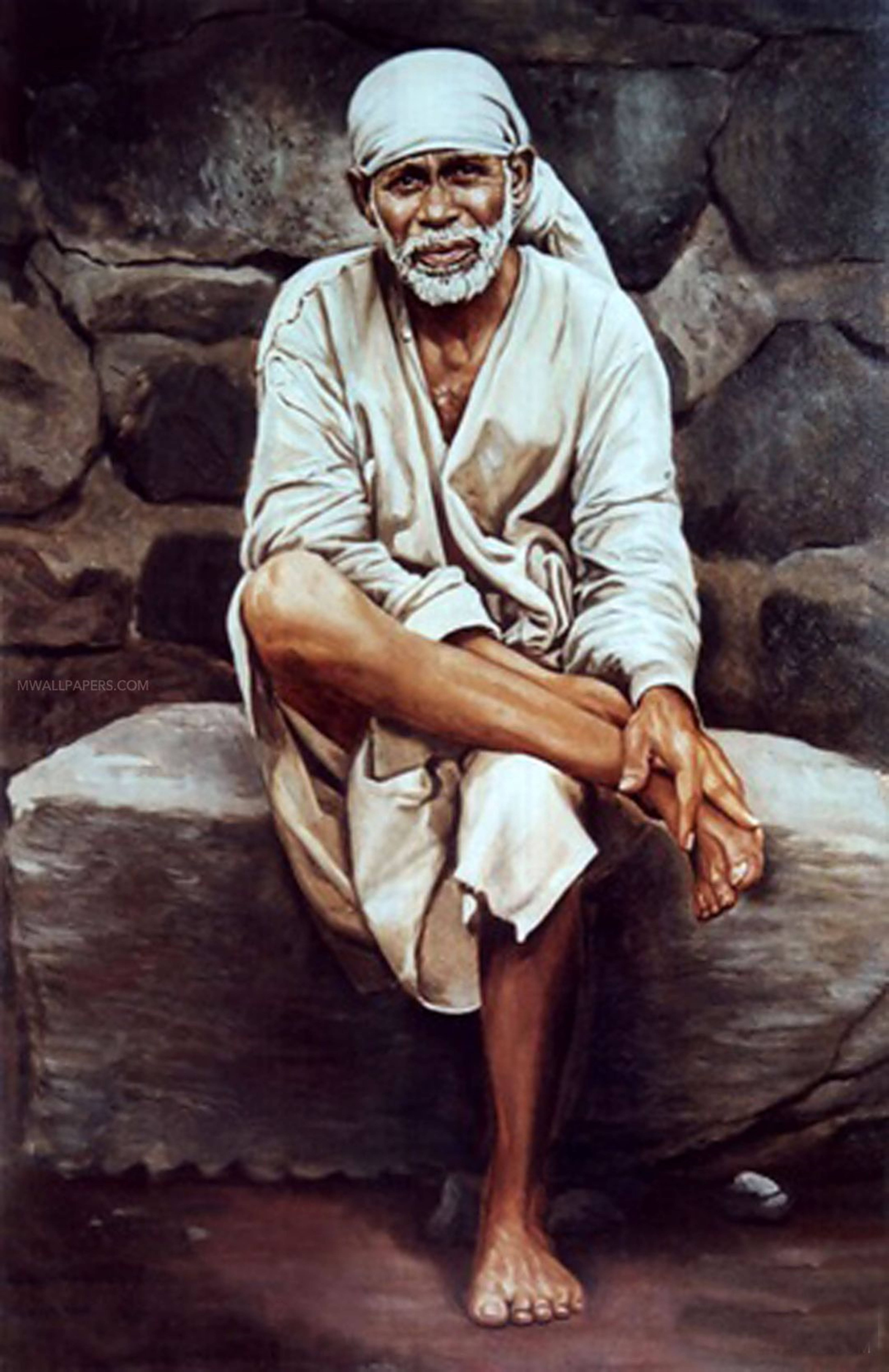 Sai Baba 恢復影像 4K 壁紙 — 一位留著白鬍子、戴頭巾的長者赤腳坐在石壁前的石台上。