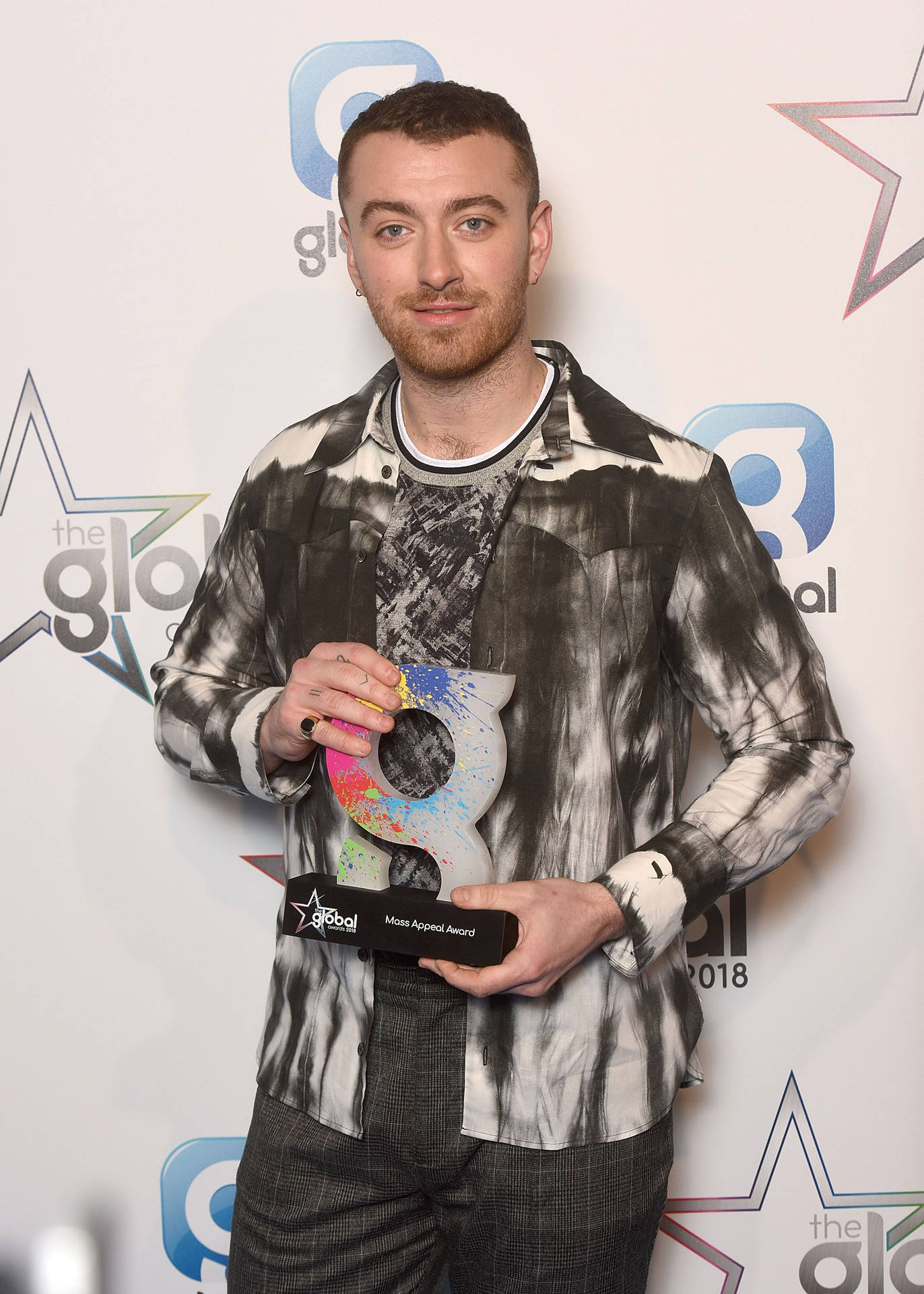 男子在Global Awards活動中手持色彩繽紛的獎項。