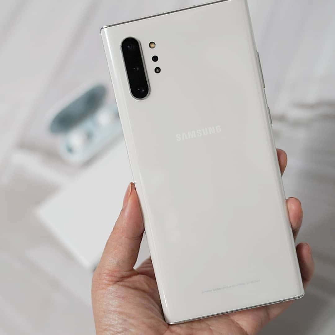 手拿著白色Samsung智能手機，相機模組可見。
