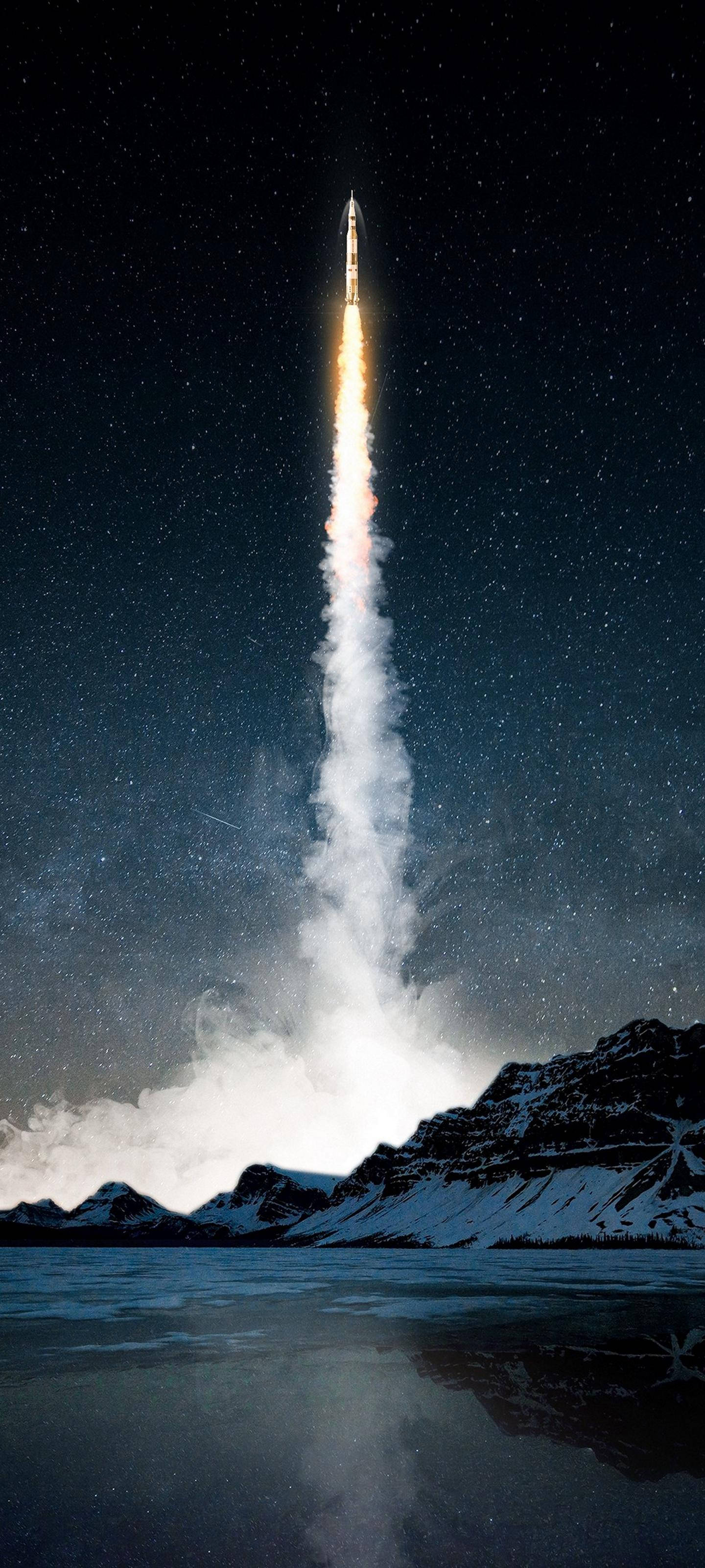 Samsung S21 Ultra火箭發射 壁紙 — 火箭在繁星點點的夜空中升空，越過積雪的山脈和冰凍的湖泊，留下一道明亮的火尾。