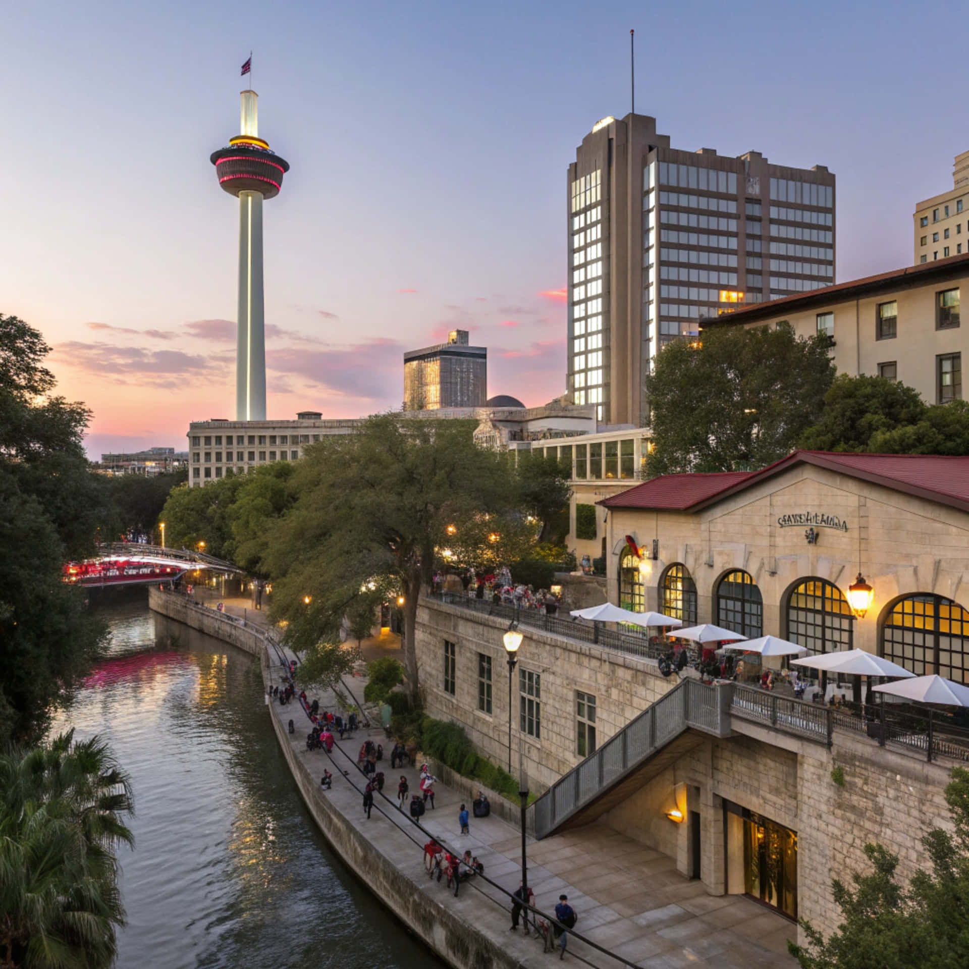San Antonio Skyline 壁紙 — 河邊黃昏時分的充滿活力的城市景觀，有高聳的照明塔和享受戶外咖啡館的人們。