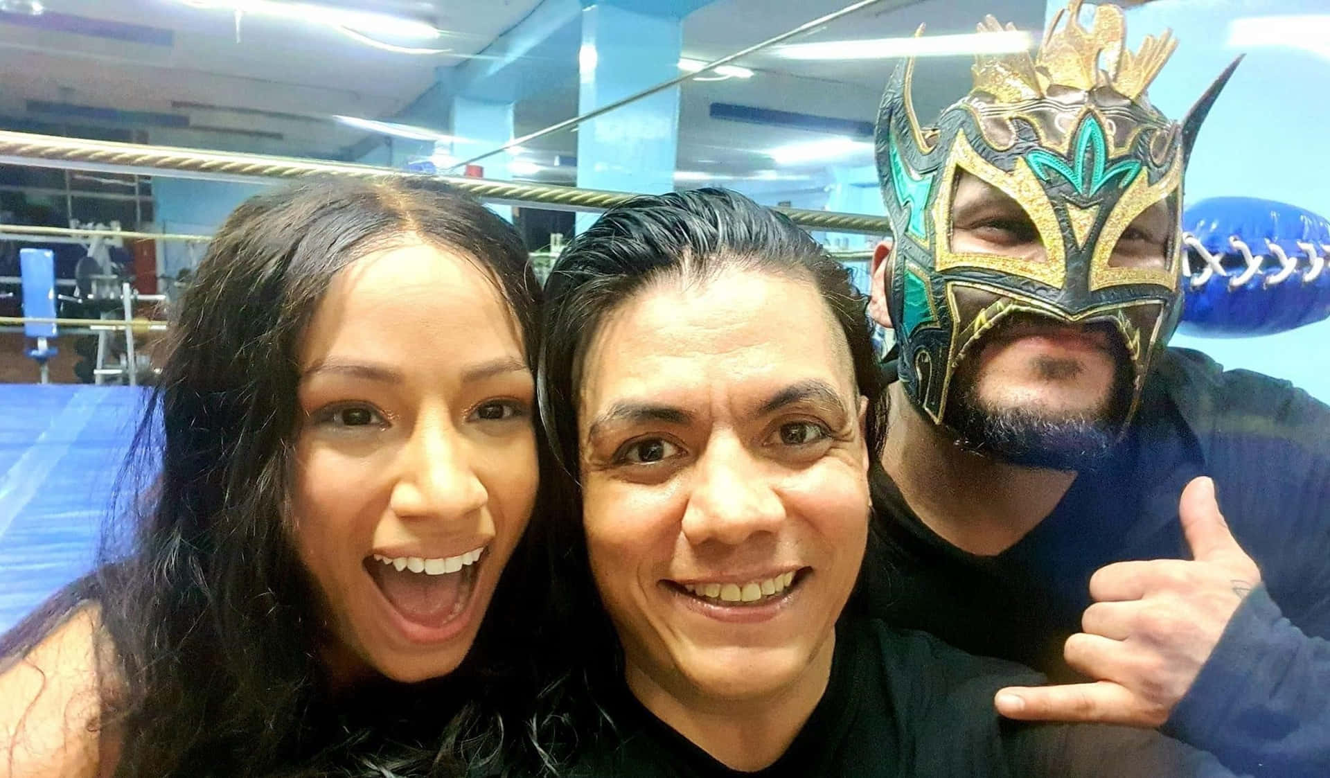  壁紙 — 三人在摔角健身房為自拍微笑，其中一人戴著華麗的 lucha libre 面具。