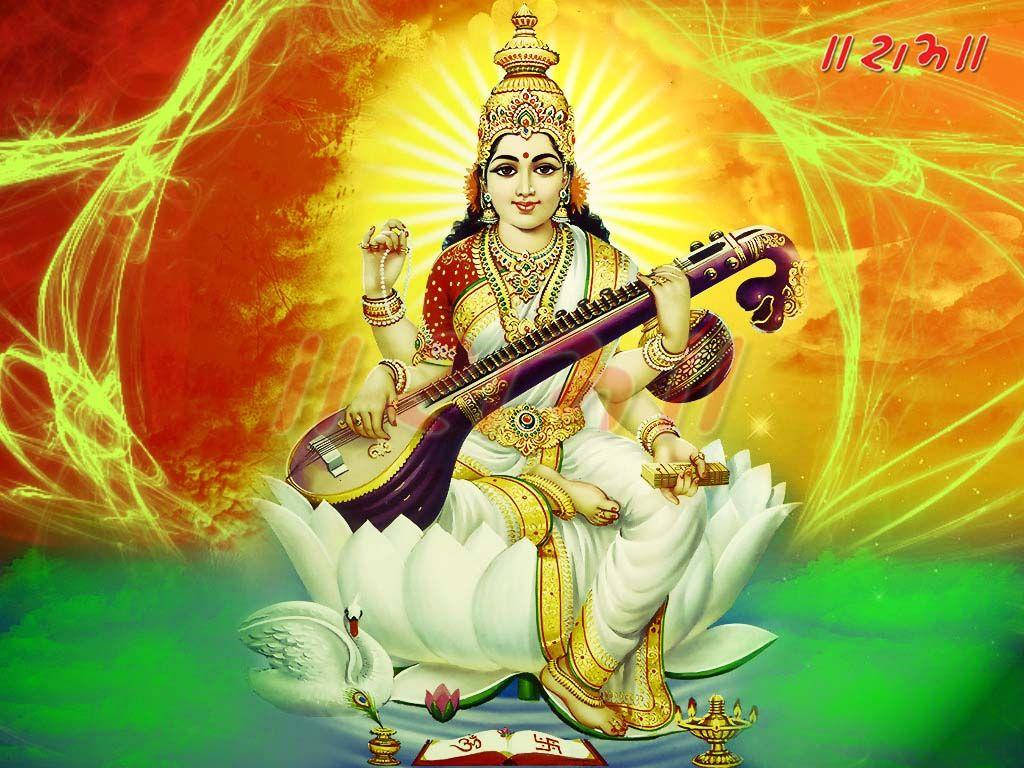 Saraswati Mata 在白色花朵中 壁紙 — 薩拉斯瓦蒂女神優雅地坐在白色蓮花上，手持維納琴，背景是光芒四射的橙色和綠色宇宙背景。