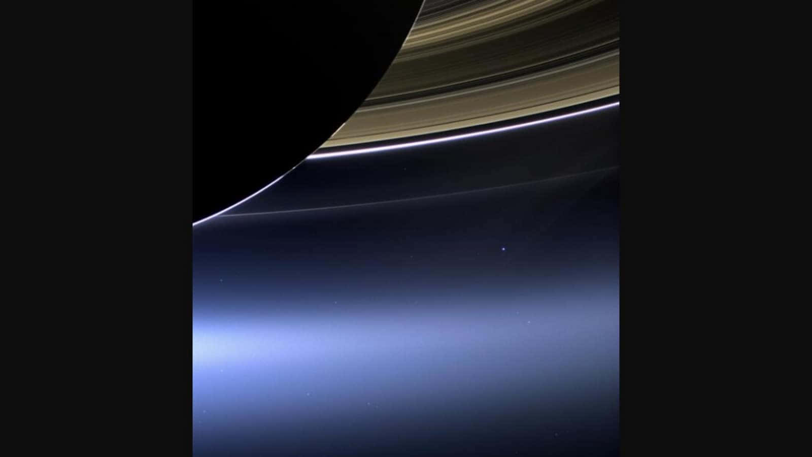 土星標誌性的環在太空的黑暗中明亮閃耀，帶有藍色大氣光芒。