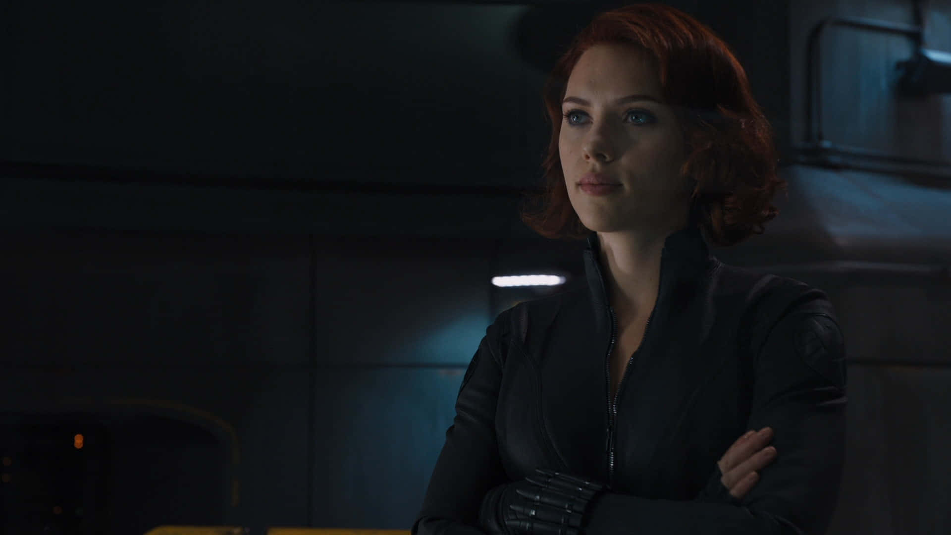 黑寡婦 桌布 壁紙 — Scarlet Witch 企喺昏暗嘅未來感房間，雙手交叉，著住黑色戰術外套，喺冰冷藍色燈光下。