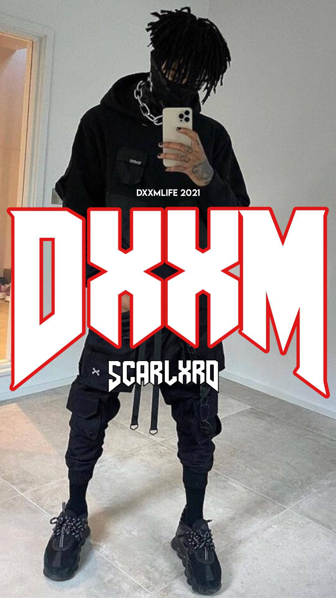 Scarlxrd DXXM 巡迴 壁紙 — 一名身穿全黑街頭服飾的人，戴著鏈條口罩和超大連帽衫，用手機對著鏡子自拍。