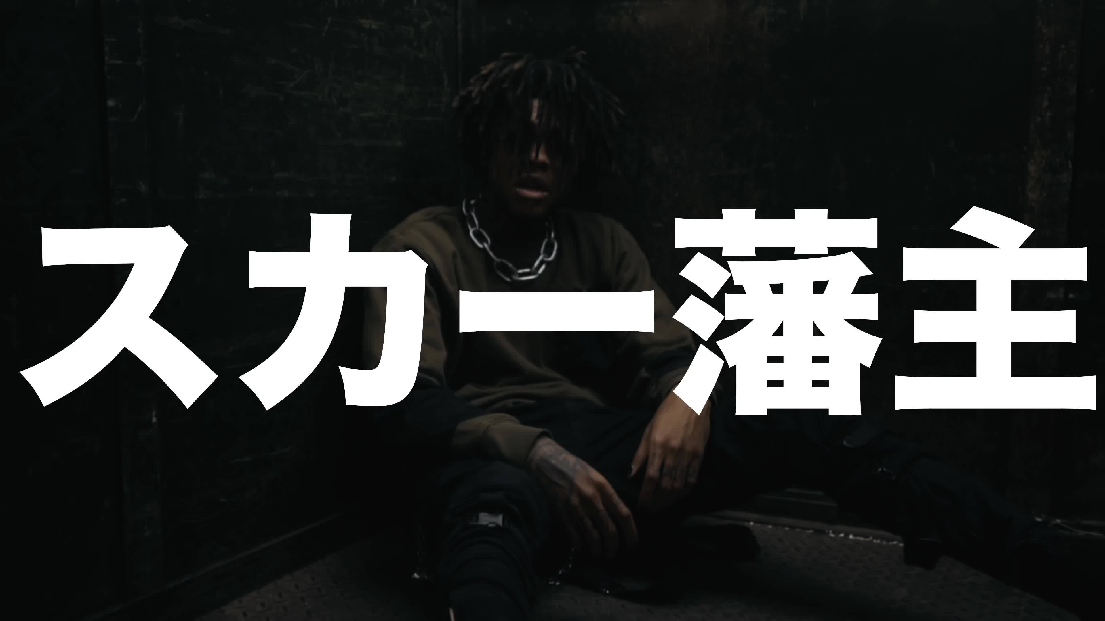Scarlxrd 帶日文名稱 壁紙 — 一個留著辮子的人坐在昏暗骯髒的空間中，上面覆蓋著粗體白色日文字。