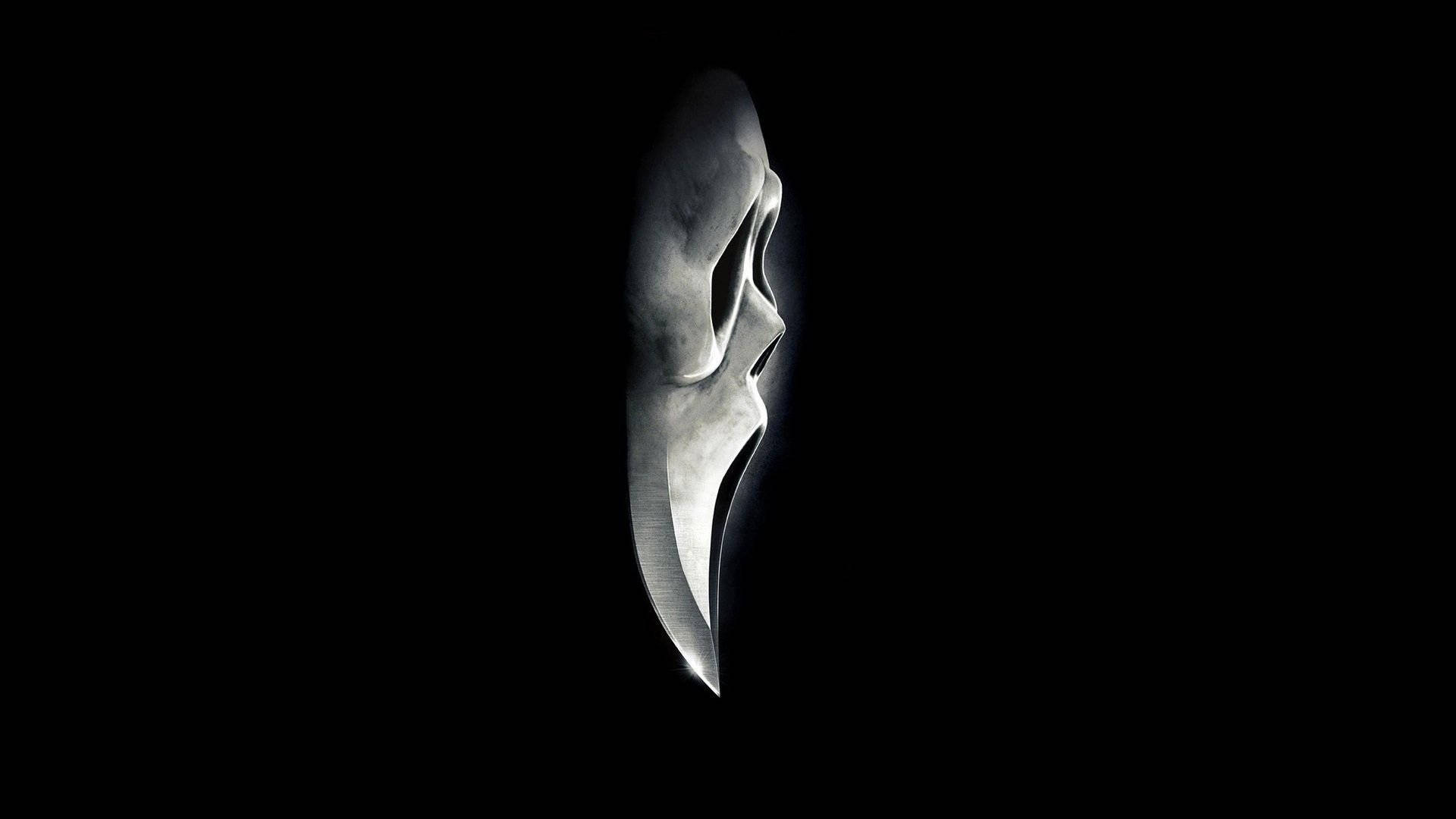 《Scream》系列中的恐怖反派Ghostface 壁紙 — 一把時尚的銀色刀在漆黑背景中發光，戲劇性的燈光突顯其銳利曲線和金屬質感。