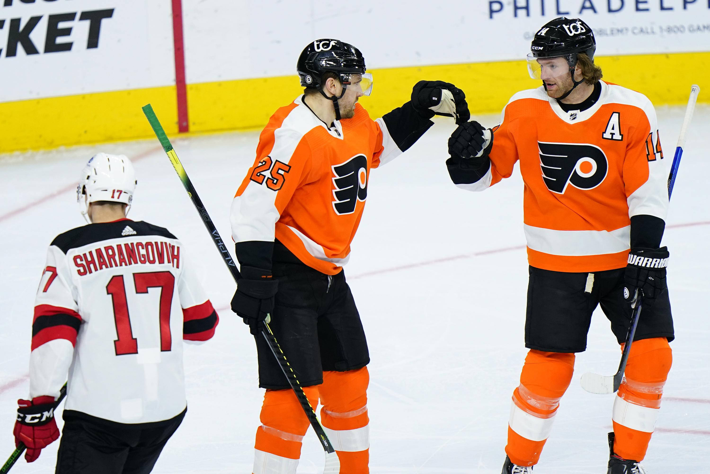 Sean Couturier 與隊友同框 壁紙 — 兩名費城飛人隊的冰球運動員穿著橙色球衣，在比賽中於冰上互相擊掌。