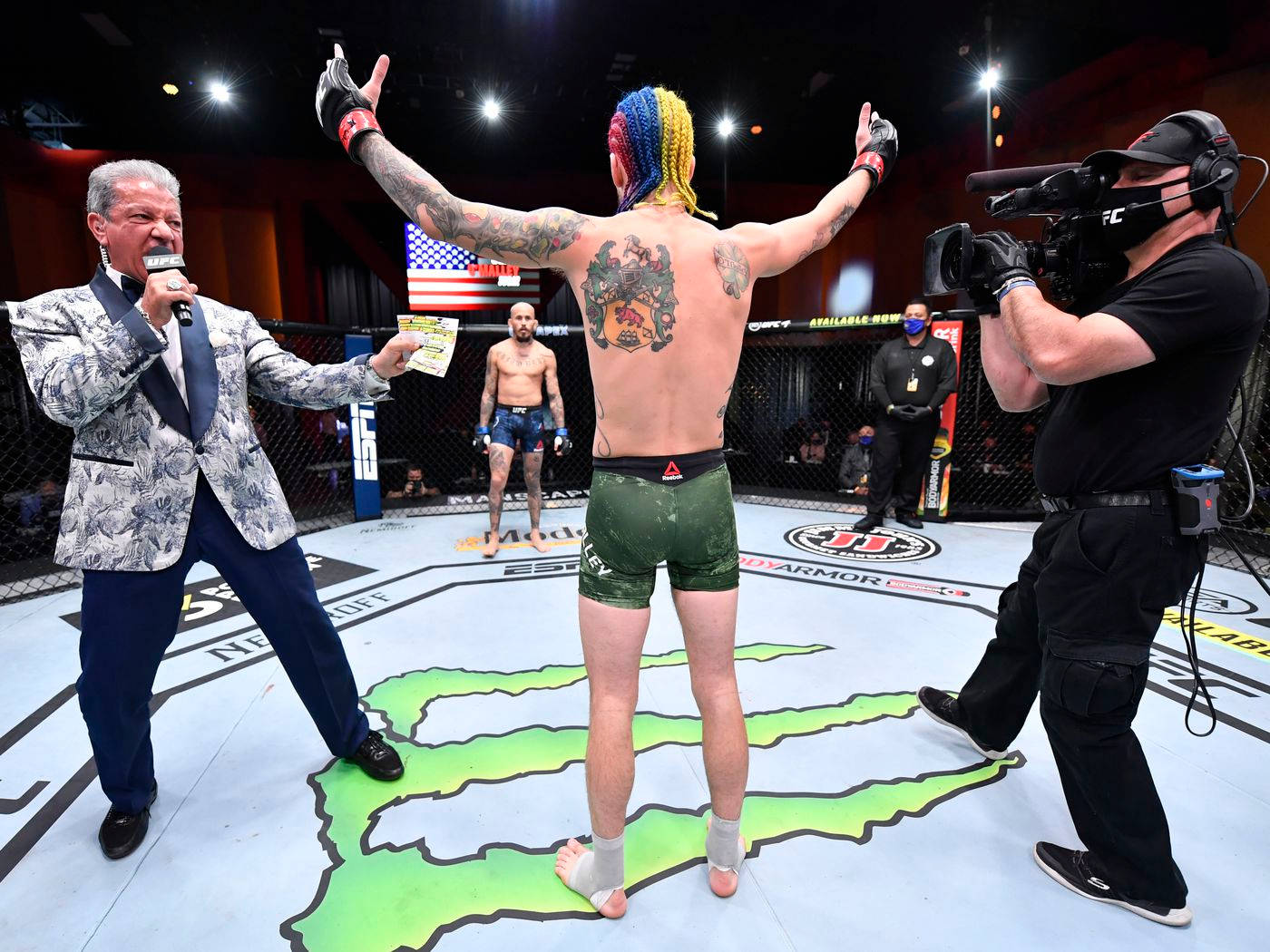 MMA拳手在八角籠中高舉雙臂慶祝勝利。