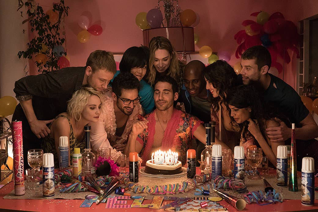《Sense8》Lito 生日慶祝 壁紙 — 一群朋友在粉紅色房間的彩色派對中圍繞著點燃蠟燭的生日蛋糕。